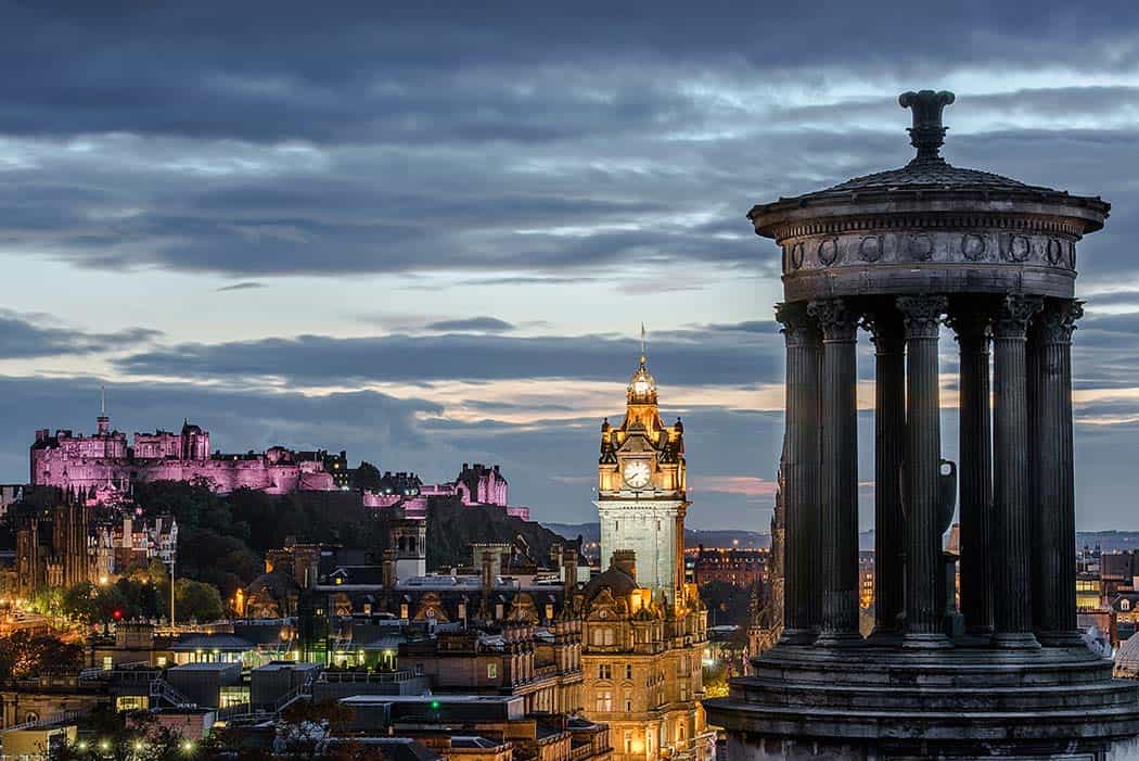 Edinburgh castle (purple lights) and the cityscape at night.