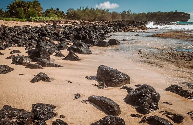 Shipwreck Beach with black volcanic boulders in Kauai