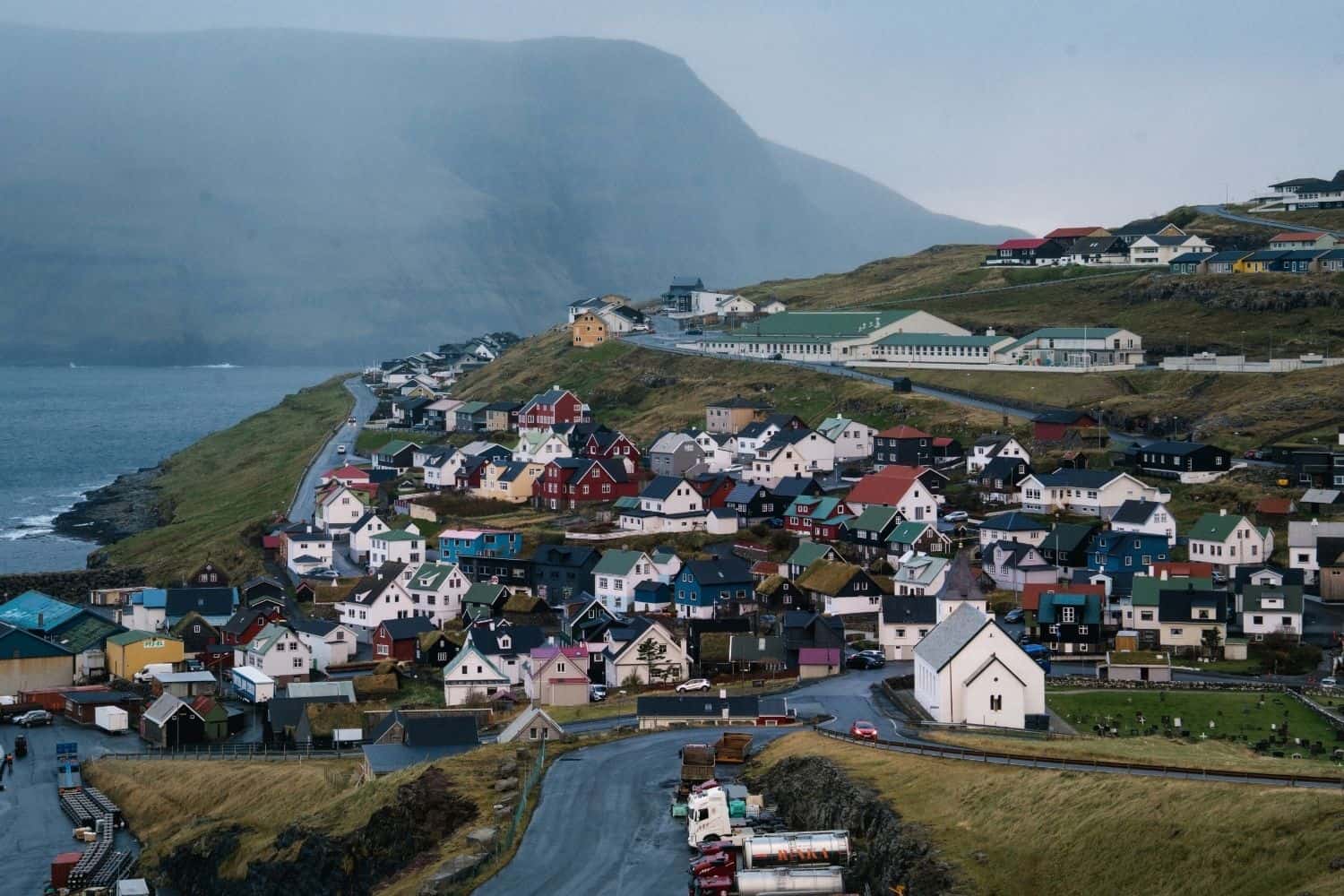 Colorful houses and church in the village of Eiði, Faroe Islands, surrounded by mountains and the ocean