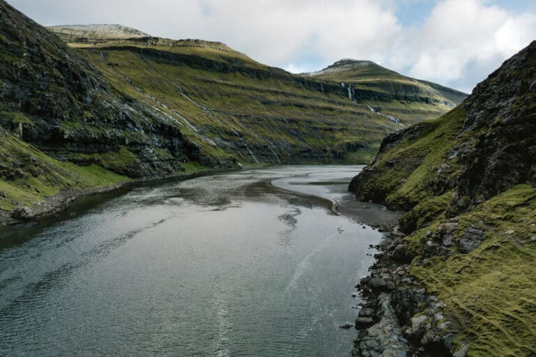 Saksun Lagoon surrounded by steep green mountains along the Ut á Lónna walk in the Faroe Islands
