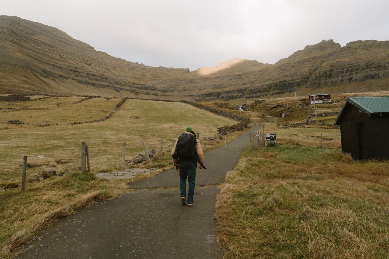 Hiker walking toward the start of the Villingadalsfjall trail near Viðareiði in the Faroe Islands